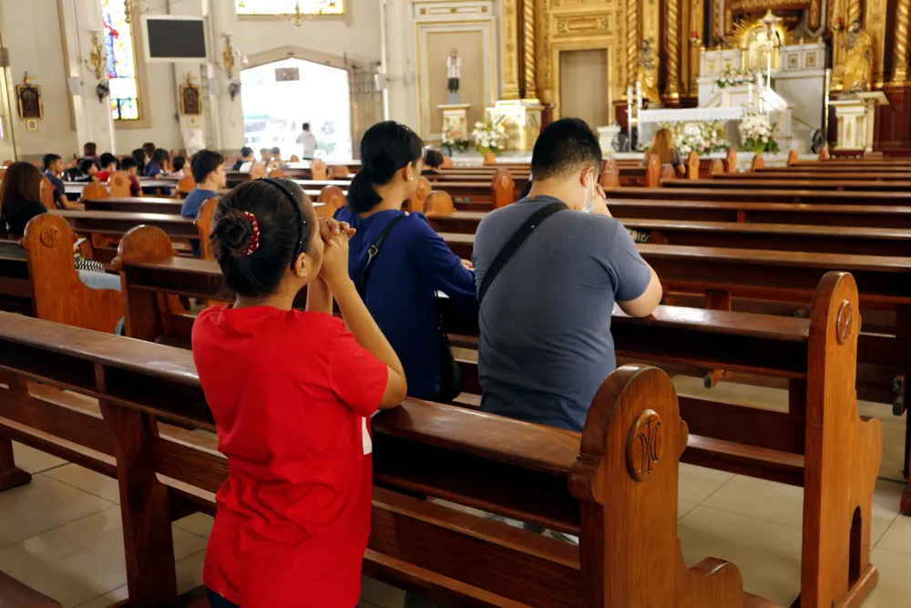 Catholic men and women kneel down and pray inside the Antipolo Cathedral in the Philippines.?w=200&h=150