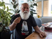 Danny Miran shows the T-shirt with a photo of his son Omri, one of the Israelis kidnapped on Oct. 7, 2023, and who is still being held hostage in Gaza. On the T-shirt, the Hebrew inscription reads: “Bring them home now!”, the motto of the campaign to bring back the hostages. A few days after Oct. 7, Danny Miran, 79, left his home in northern Israel and joined the Hostages and Missing Families Forum in Tel Aviv. His life’s purpose has become bringing his son back home.