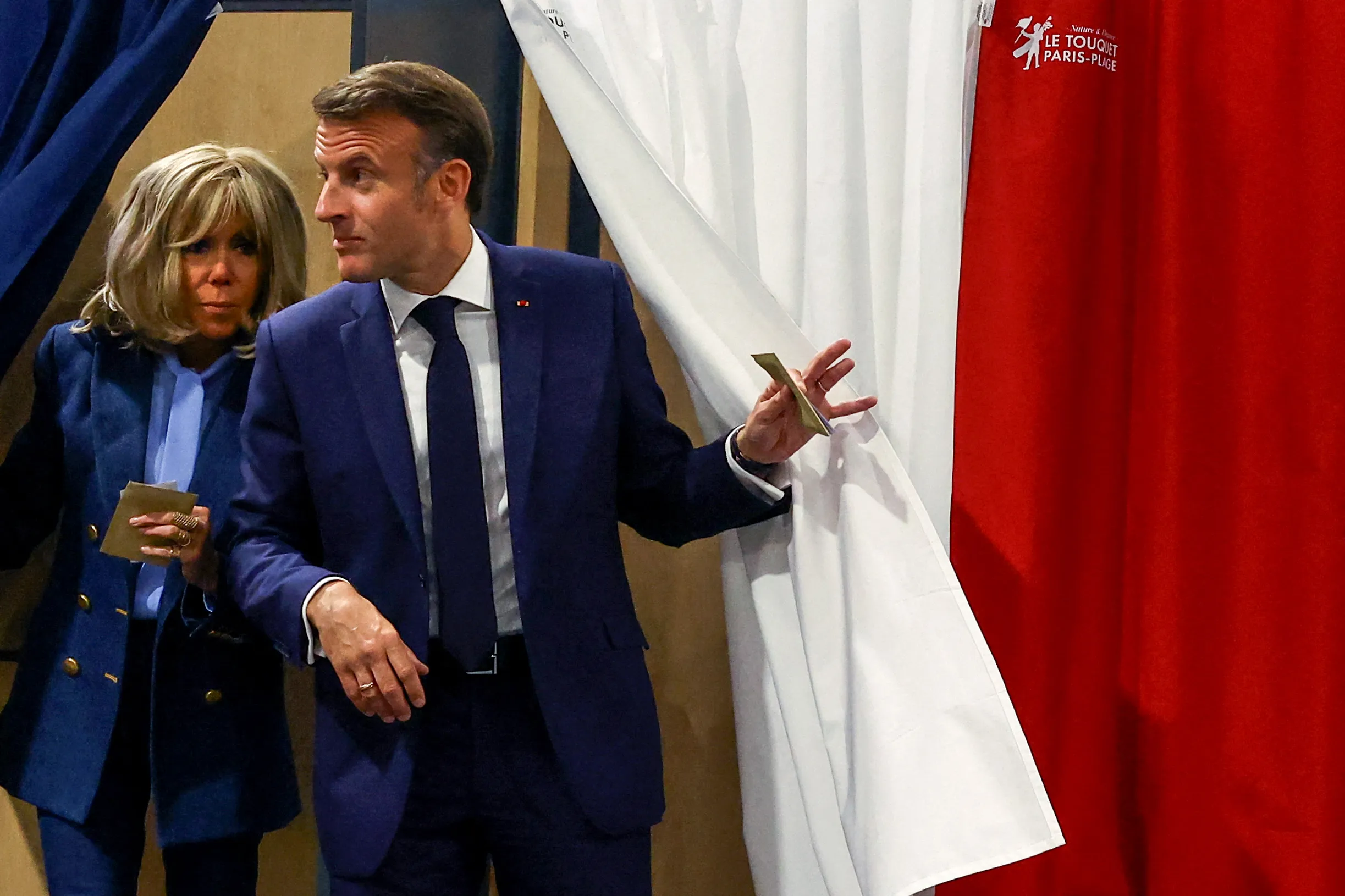 French President Emmanuel Macron and his wife, Brigitte Macron, exit a polling booth adorned with curtains displaying the colors of the flag of France before casting their ballot for the European Parliament election at a polling station in Le Touquet, northern France, on June 9, 2024.?w=200&h=150