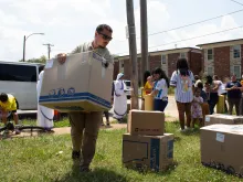 Perpetual Pilgrim Patrick Fayad lifts a heavy "Box of Mercy" filled with donations for refugee families.